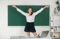 Portrait of a young, confident and attractive female student excited amazet student with raised hands in school