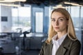 Portrait of a young confident blonde businesswoman in a suit standing in the office and smiling at the camera. Close-up Royalty Free Stock Photo