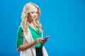 Portrait of young confident blonde, use the phone, blue background Royalty Free Stock Photo