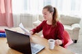 Portrait of young confident business woman sitting at wood desk, drinking coffee and reading documents at home office Royalty Free Stock Photo