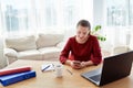 Portrait of young confident business woman sitting at wood desk with laptop computer at home office and using mobile smart phone, Royalty Free Stock Photo