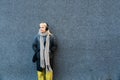 Portrait of young confident independent stylish hipster woman standing against black wall with wireless headphones listening music Royalty Free Stock Photo