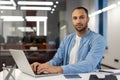 Portrait of a young confident Muslim man working and studying in the office, sitting at a desk with a laptop in casual Royalty Free Stock Photo