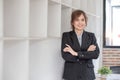 Portrait, Young confident smiling Asian business woman wearing suit standing in office with arms crossed. Royalty Free Stock Photo