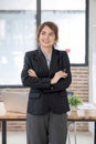 Portrait, Young confident smiling Asian business woman wearing suit standing in office with arms crossed. Royalty Free Stock Photo