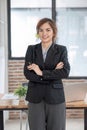 Portrait, Young confident smiling Asian business woman wearing suit standing in office with arms crossed. Royalty Free Stock Photo