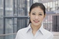 Portrait of young confident smiling businesswoman, building exterior in the background