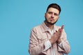 Portrait of young confident unshaven man keeps hands together, wearing pink jeans jacket and white shirt, stands against Royalty Free Stock Photo