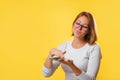 Portrait of a young contented woman wasting money. Yellow background. Copy space. The concept of success and wealth