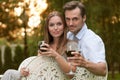 Portrait of young couple having red wine on chairs in park Royalty Free Stock Photo