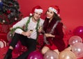 Portrait young couple holding glasses of champagne and smiling while celebrating on red background. christmas and happy new year Royalty Free Stock Photo