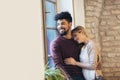 Young couple hugging next to the window, brick wall background Royalty Free Stock Photo