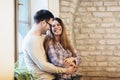 Young couple hugging next to the window, brick wall background