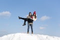 Portrait of young couple in love on snow-covered hill against blue sky. Guy holds the girl in his arms Royalty Free Stock Photo