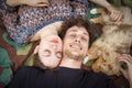 Portrait of young couple lying down on a field with doggie