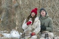 Portrait of young couple are sitting hugging each other in a snow-covered winter park, wrapping themselves in a plaid. Man and Royalty Free Stock Photo