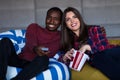 Portrait of young couple sitting on sofa watching a movie with expression on their faces Royalty Free Stock Photo