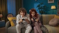 Portrait of young couple spending time together. Man and woman in pajamas sitting on the sofa, playing video games. Royalty Free Stock Photo