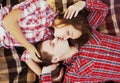 Portrait of young couple teenagers kissing lying together on plaid, top view