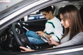 Portrait of a young couple use phones, texting and driving together, as seen through the windshield Royalty Free Stock Photo