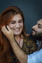 Portrait of a young couple where the young man with beard and long hair caresses the face of the young woman with long red hair Royalty Free Stock Photo