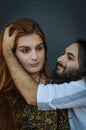 Portrait of a young couple where the young man with beard and long hair caresses the head of the young woman with long red hair Royalty Free Stock Photo