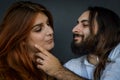Portrait of a young couple where the young man with beard and long hair caresses the face of the young woman with long red hair Royalty Free Stock Photo