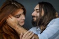 Portrait of a young couple where the young man with beard and long hair caresses the face of the young woman with long red hair Royalty Free Stock Photo