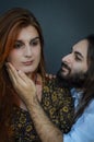Portrait of a young couple where the young man with beard and long hair caresses the face of the young woman with long red hair Royalty Free Stock Photo