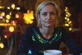 Portrait of a young cozy with cup of coffee, cookie and Christmas lights and pine branch. Royalty Free Stock Photo