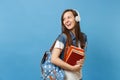 Portrait of young curious woman student with backpack headphones listening music hold school books looking aside on copy Royalty Free Stock Photo