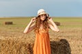 Portrait of a young curly girl in a retro hat and vintage sundress on a harvested wheat field Royalty Free Stock Photo