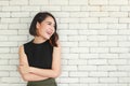 Portrait of young and cute Asian woman standing against white brick wall crossed arms in self-confident pose and smile with Royalty Free Stock Photo