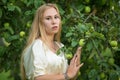 Portrait of a young cute blonde white girl near the tree with green apples. Royalty Free Stock Photo