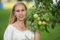 Portrait of a young cute blonde white girl near the tree with green apples. Royalty Free Stock Photo