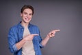 Cute cheerful young man in a denim shirt shows fingers to the side Royalty Free Stock Photo