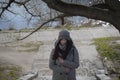 Portrait of young cute girl standing outdoors and thinking. Young Caucasian woman in warm coat and hat spending sunny Royalty Free Stock Photo