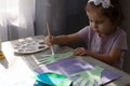 Portrait of a young cute kid girl holding a paintbrush and painting painting at the table. Creativity, education, child Royalty Free Stock Photo