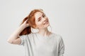 Portrait of young cute redhead girl smiling looking at camera touching hair over white background. Royalty Free Stock Photo