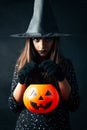 Portrait of a young cute witch holding a Halloween pumpkin basket Royalty Free Stock Photo