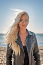 Portrait of a young cutie blond girl in a leather jacket with hair flying from the wind on the beach Royalty Free Stock Photo