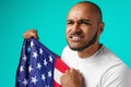 Portrait of young dark-skinned man proudly holding USA flag