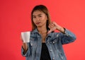 Young dissapointed attractive asian girl holding coffee with thumbs down in studio Royalty Free Stock Photo