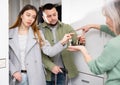 Couple returning keys to woman at doorway