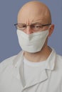 Portrait of a young doctor with glasses and mask, light blue background. Looking at the viewer, intense facial features Royalty Free Stock Photo