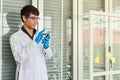 Portrait of young doctor scientist wearing safty glasses and blue rubber gloves using mobile smartphone in working laboratory room