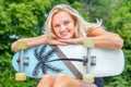 Young blonde woman with skateboard on lap