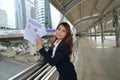 Portrait of young elegant Asian businesswoman presenting business profits or charts on outdoor city background. Royalty Free Stock Photo