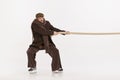 Portrait of young emotive man in winter clothes pulling rope isolated over white studio background. Competition Royalty Free Stock Photo