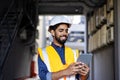 Portrait of young engineer worker, man in helmet and vest using tablet computer, smiling, checking production figures Royalty Free Stock Photo